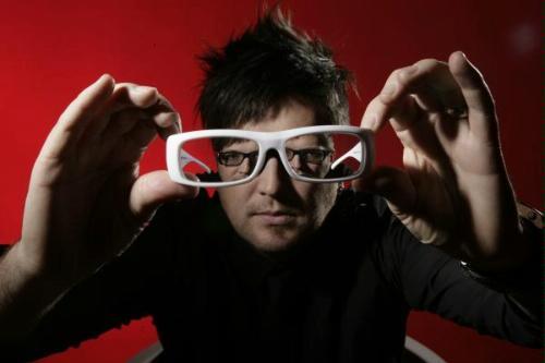 Portrait of Christian DJ Andy Hunter. Hunter holds his glasses towards the camera to show his whole face in each frame of his glasses.